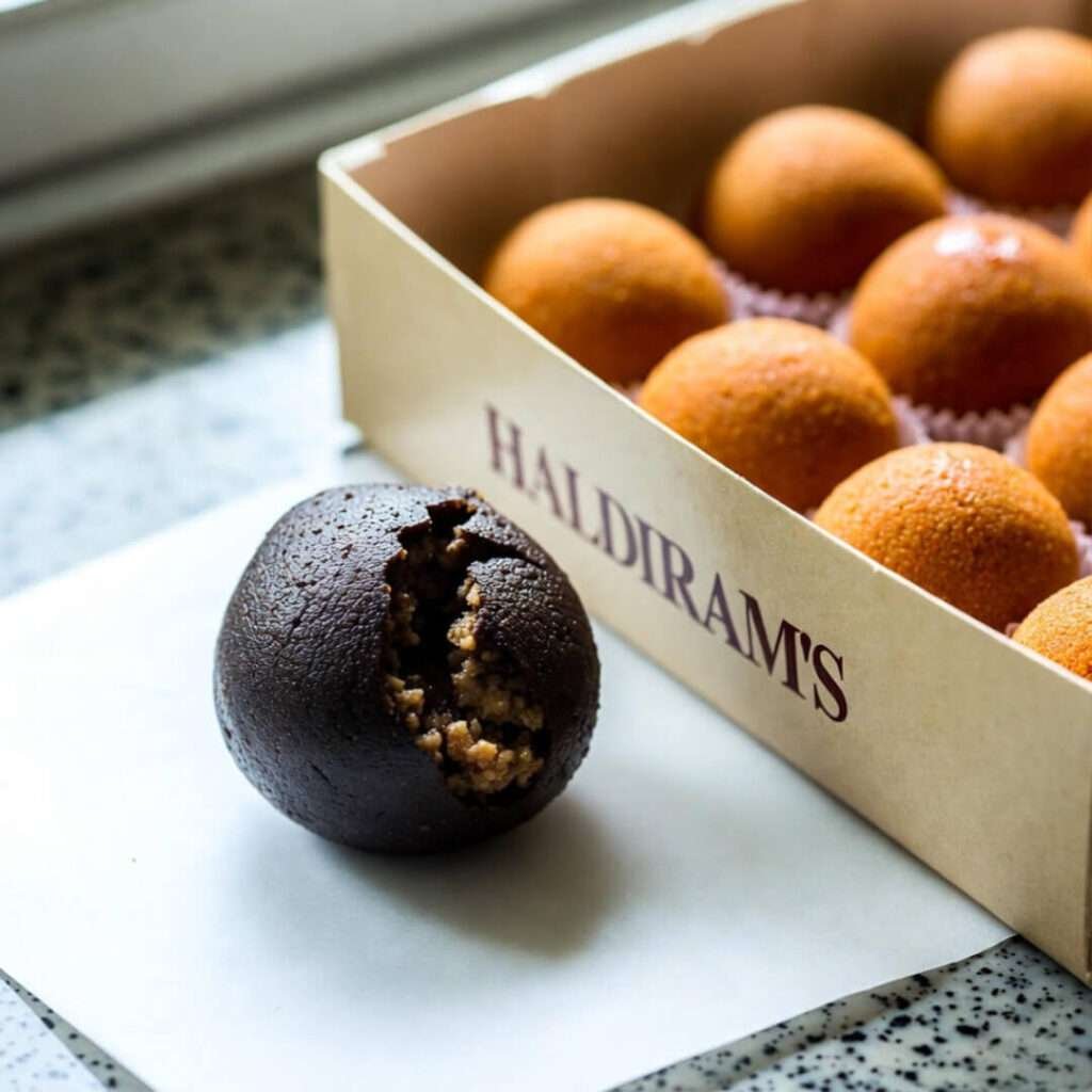 Charred failed besan laddoo beside perfect Haldiram's box