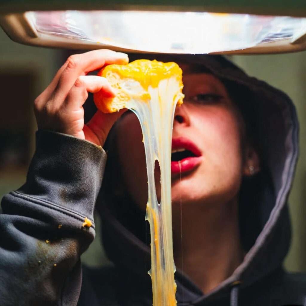 Insane fridge-light cheese pull on stained hoodie sleeve.