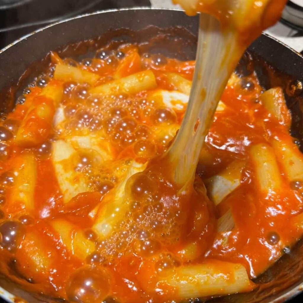 Cheesy tteokbokki pull in scratched pan, neon sauce