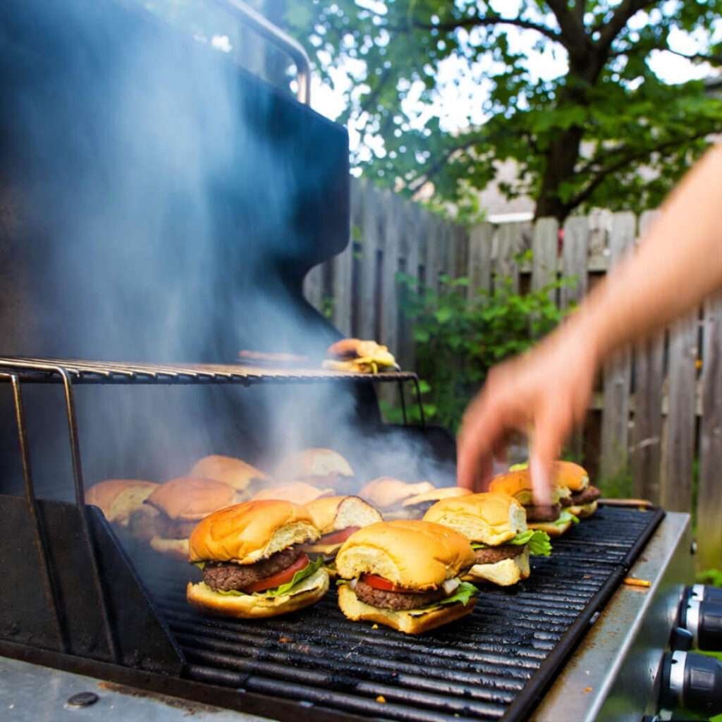 Blurry hand stealing hot slider from grill