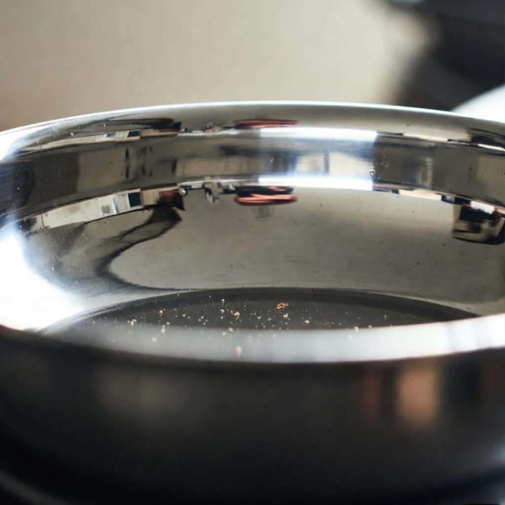 Empty brownie pan corner with crumbs and warped reflection.